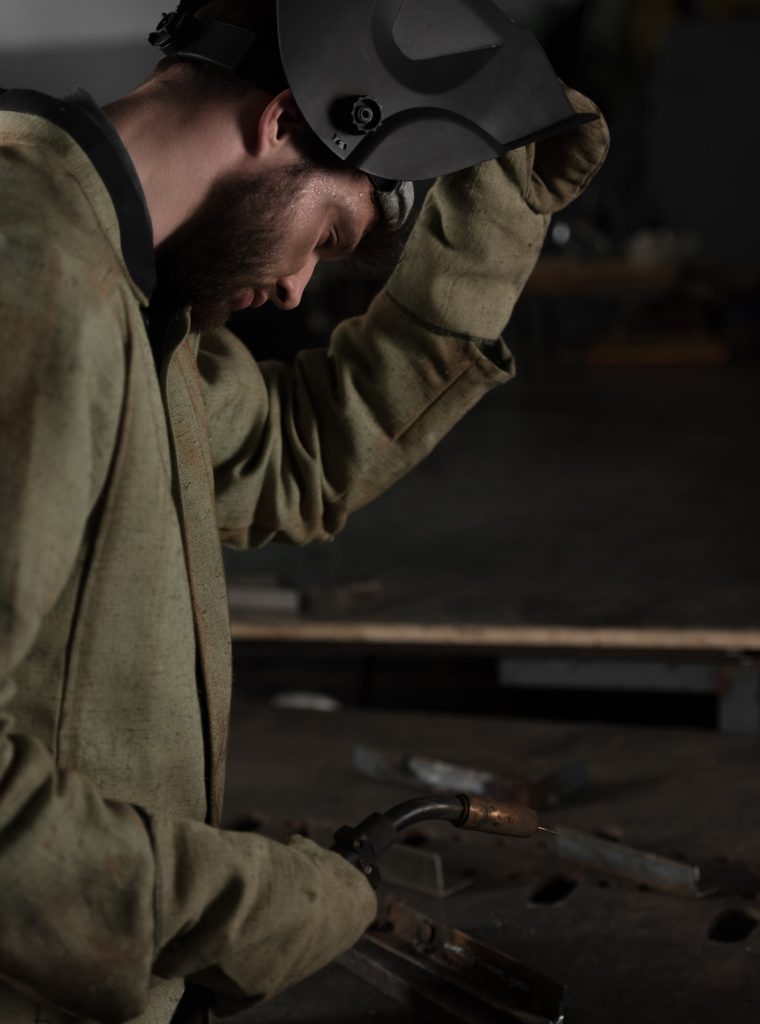 side-view-of-welder-lifting-up-protective-mask-to-look-at-his-work.jpg